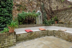 A stone bench with potted plants and a small window. - Secret Garden Square, by Veeve (London)