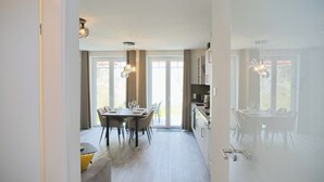 Una cucina moderna con zona pranzo, ampie finestre e una porta scorrevole che dà su uno spazio esterno.