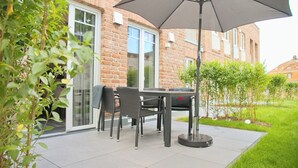 Un patio con tavolo e sedie, un barbecue e un grande ombrellone.