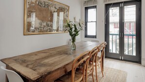 A dining area with a wooden table, chairs, a vase with flowers, and a large framed artwork on the wall. - South Kensington Mews Hideaway, by Veeve (London)
