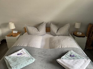 A double bed with two pillows, a bedside table with a lamp, and a bedside table with a charging device. - "Zum Kuckuck" Apartment by Gästehaus Sandvoss, Near Lake Titisee (Titisee-Neustadt)