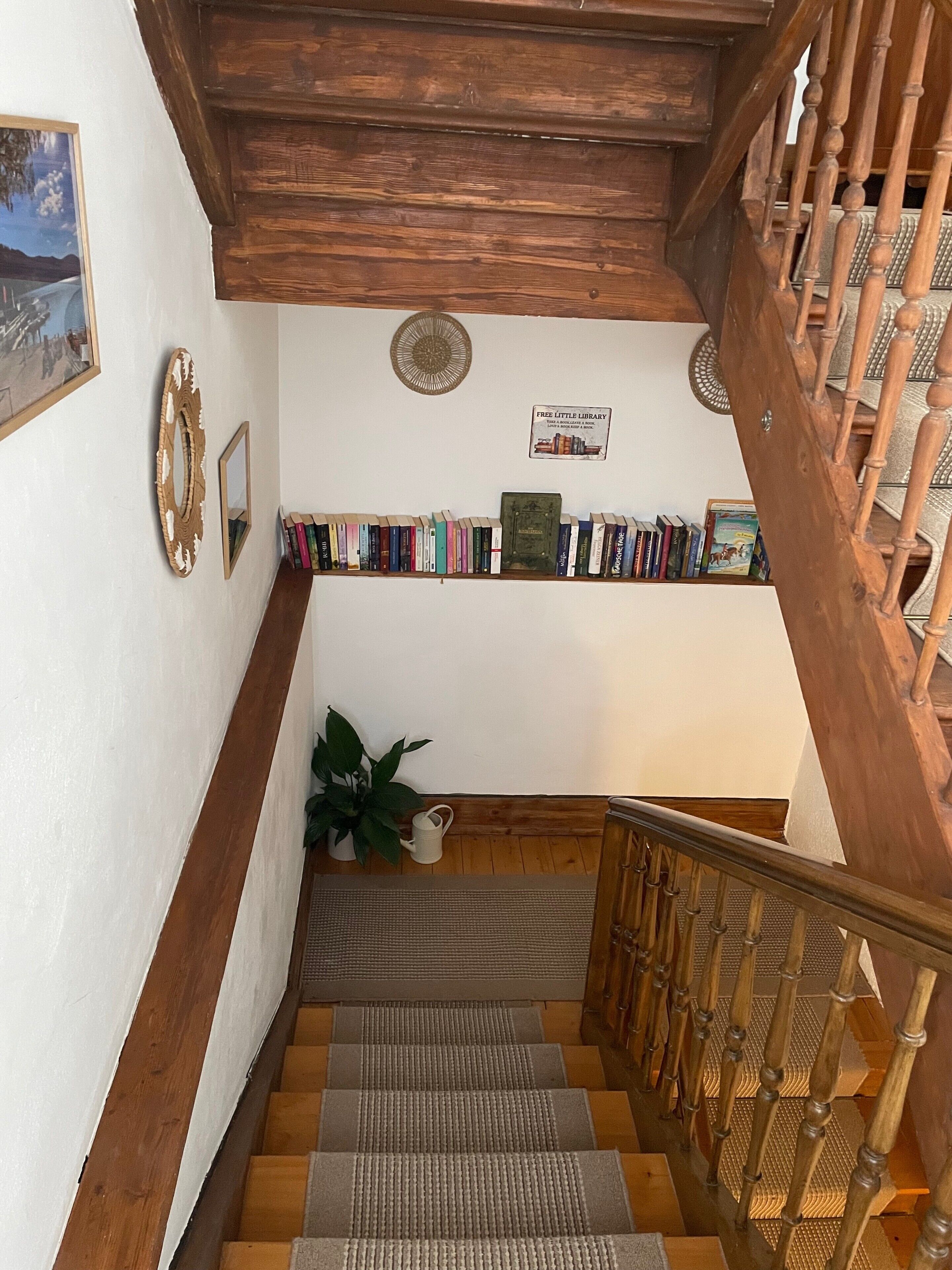 Eine Treppe mit hölzernen Geländern und einer Bücherwand voller Bücher.