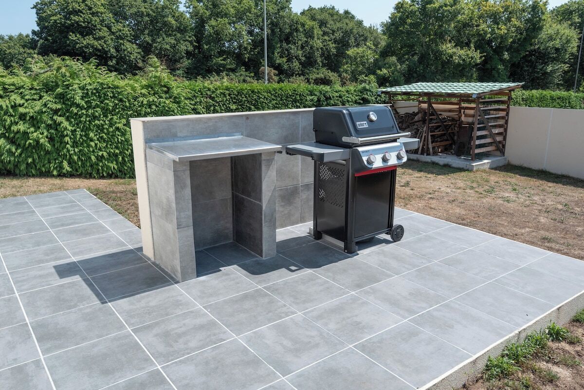 Una cocina exterior con una parrilla empotrada y una zona de cocción separada.