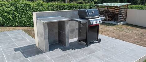 Una cocina exterior con una parrilla empotrada y una zona de cocción separada.