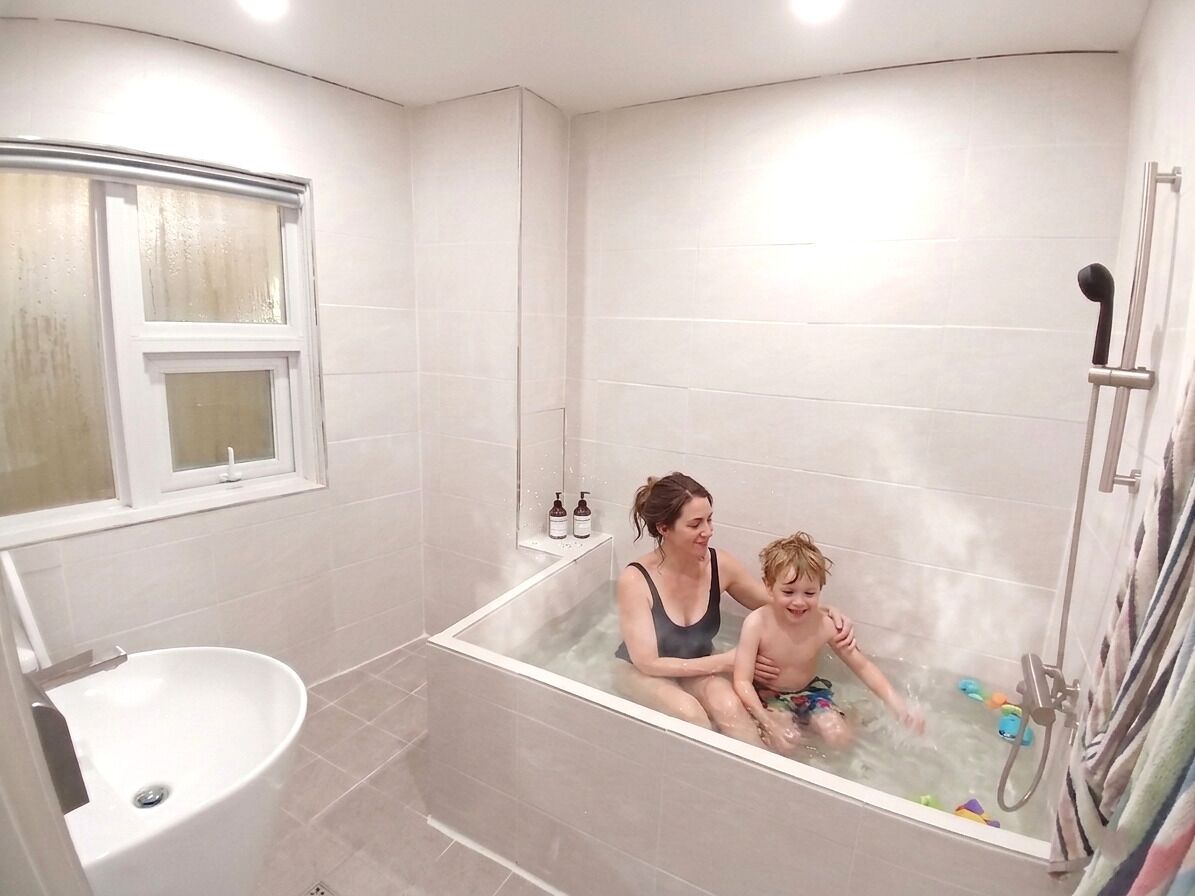 A bathroom with a bathtub, a window, and a shower.