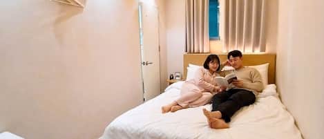 A bedroom with a bed, a bedside table, and a window with curtains.
