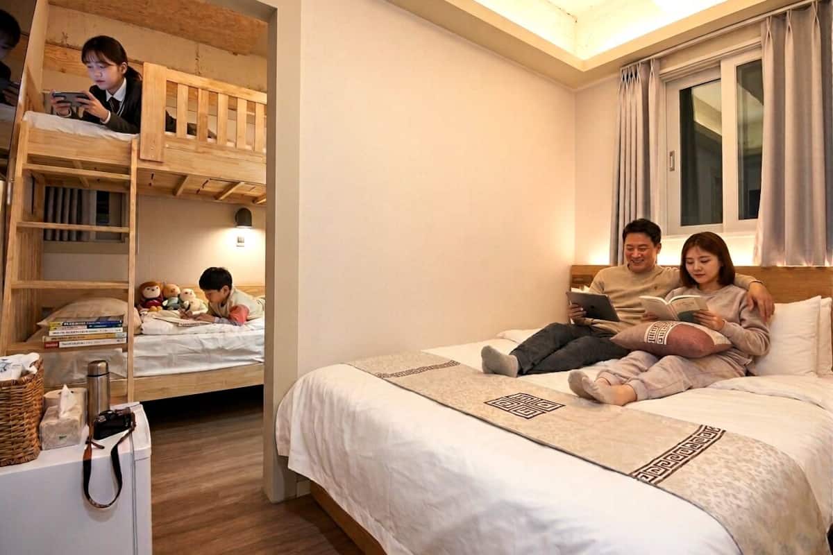 Un dormitori amb lliteres, una taula de nit i una finestra amb cortines.