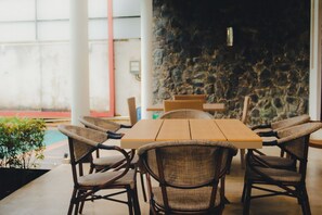 A dining area with a stone wall, a pool, and outdoor seating.