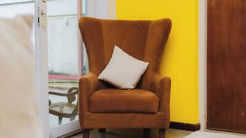 A brown armchair with a white pillow in a room with a yellow wall and a wooden door.