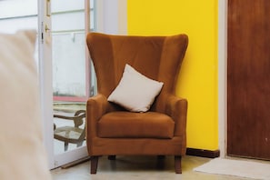 Un sillón marrón con un cojín blanco en una habitación con pared amarilla y puerta de madera.