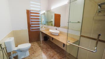 Un baño moderno con cabina de ducha de vidrio, inodoro y lavabo con espejo.