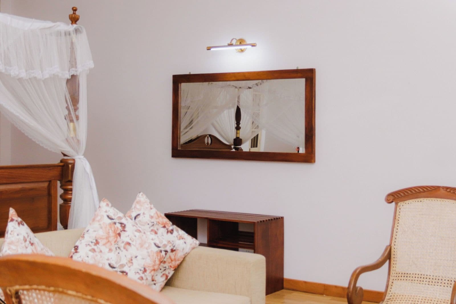 Ein Zimmer mit einem Bett, einem Nachttisch, einem Stuhl und einem an der Wand befestigten Spiegel.