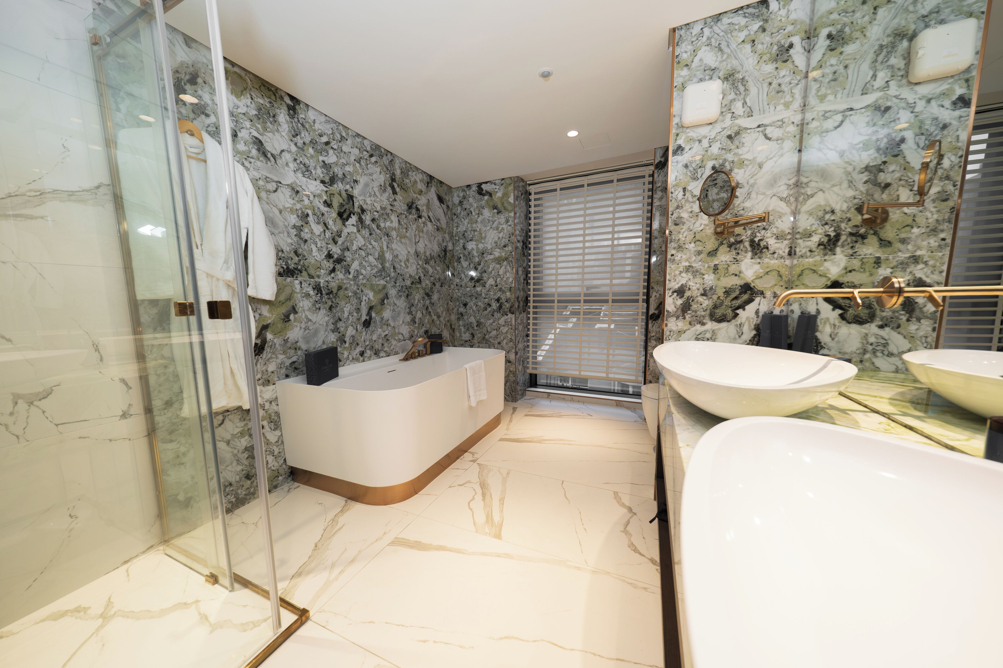 A modern bathroom with a glass-enclosed shower, a freestanding bathtub, and two sinks.