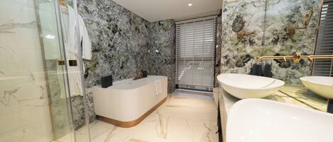 A modern bathroom with a glass-enclosed shower, a freestanding bathtub, and two sinks.