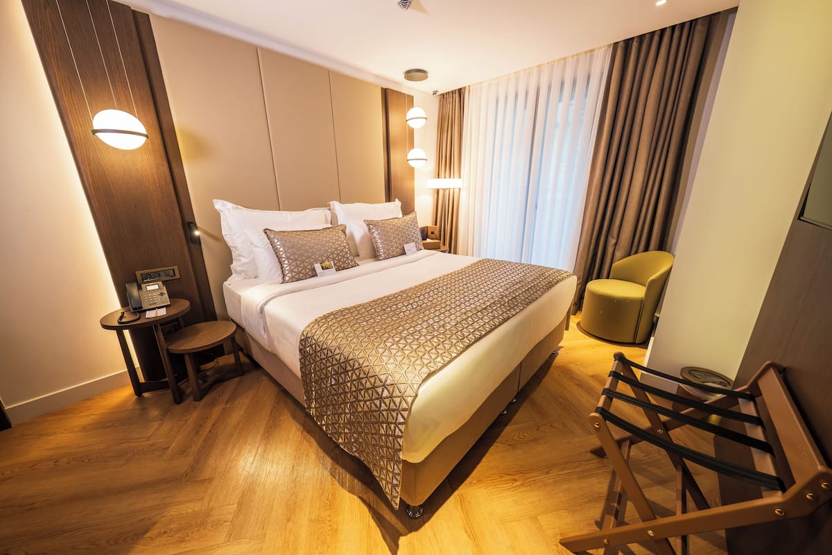 A hotel room with a large bed, bedside tables, a chair, and a TV.