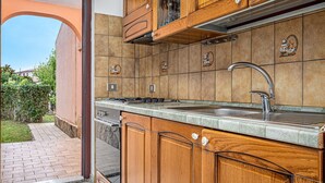 A kitchen with wooden cabinets, a stainless steel sink, and a tiled backsplash. - Apartment 'Sardegnadream 6' with Private Terrace, Wi-Fi and Air Conditioning (Suaredda-traversa)