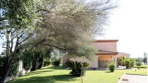 Un bâtiment doté d’un toit plat et d’un grand arbre devant.