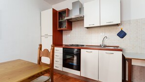 Cozinha com armários brancos, mesa de madeira, forno embutido e fogão a gás.
