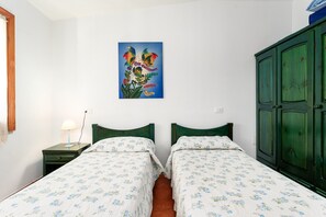 A room with two beds, a green wardrobe, a wall-mounted painting, and a bedside table with a lamp. - Holiday Home 'Ulivo A Fuile Mare' with Mountain View, Wi-Fi & Air Conditioning (Sas Linnas Siccas)