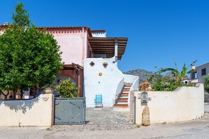 A building with a curved facade, a blue chair outside, and a stone staircase leading to the entrance. - Orosei Domo Holiday Home with Mountain View, Private Terrace & Air Conditioning (Orosei)