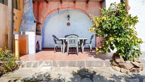 Un patio esterno con tavolo e sedie, un muro in pietra e una pianta in vaso.