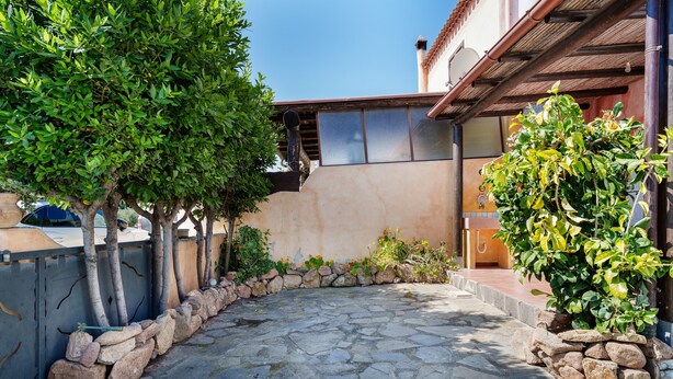 Un cortile con pavimento in pietra, un muro in pietra e una pergola in legno.