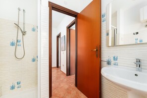 Un bagno con doccia, lavandino e specchio.