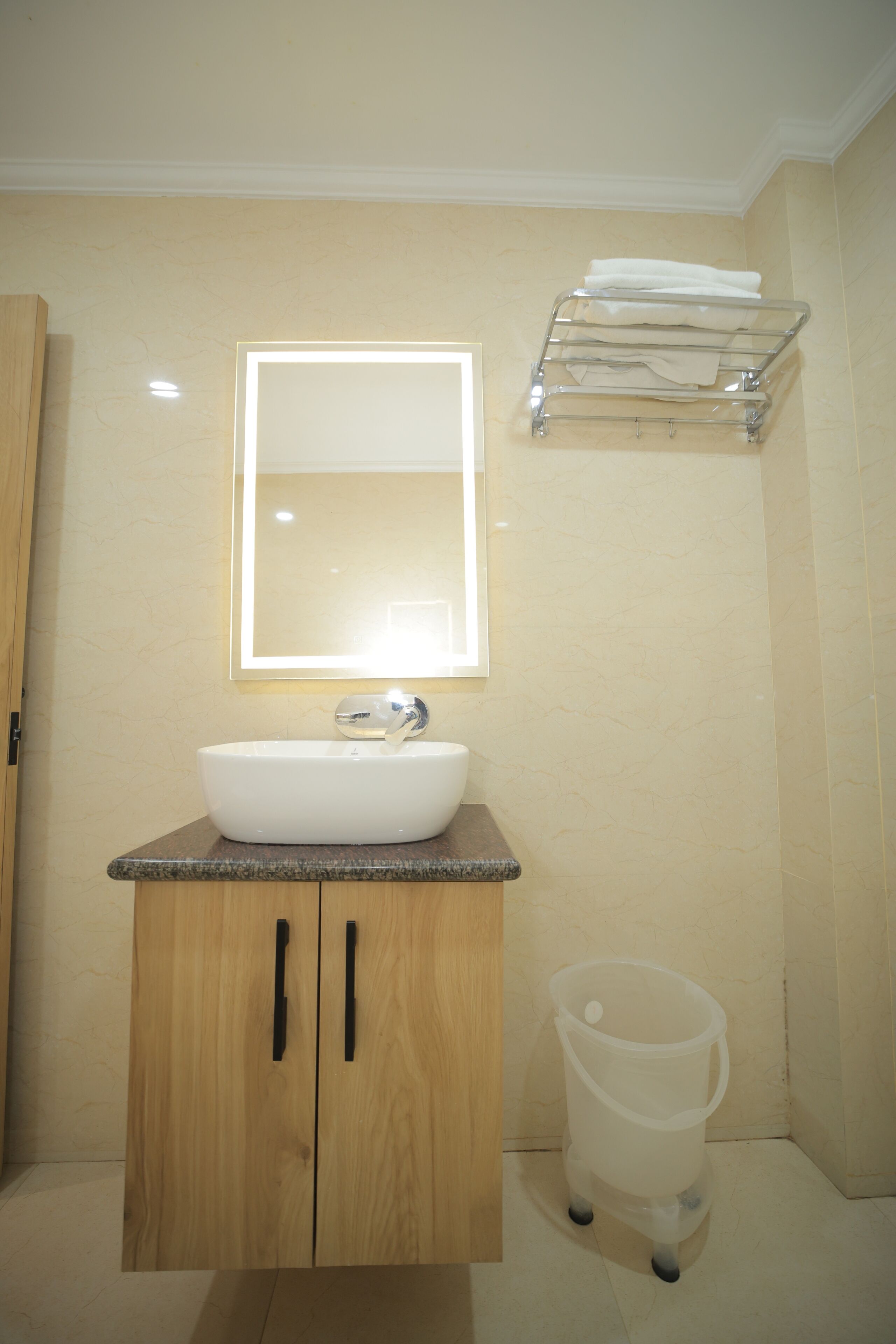 A bathroom with a white sink, wooden cabinets, a mirror, and a towel rack.