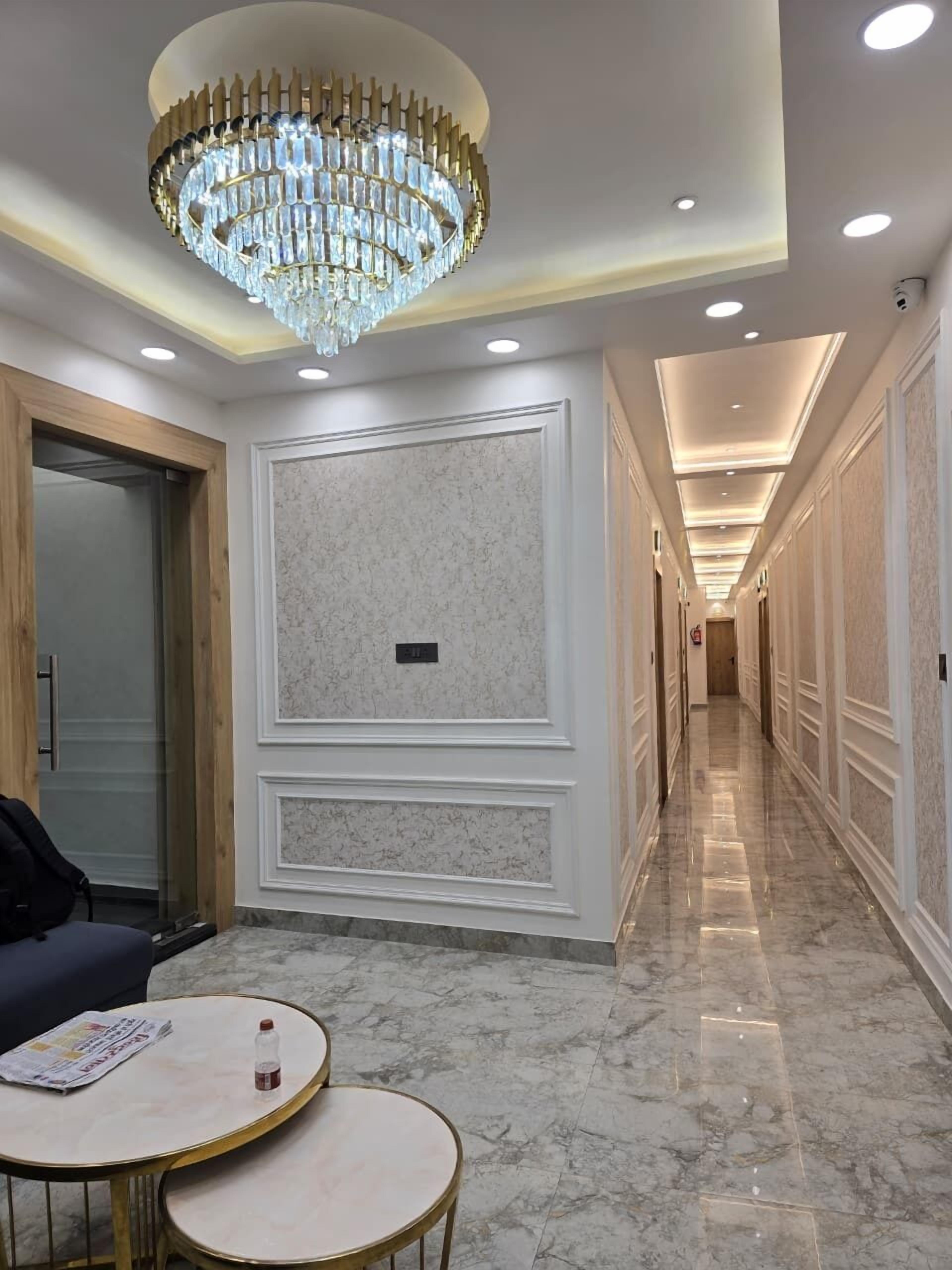 Ein Hotelkorridor mit einer Chandelüster, Marmorwänden und einer Sitzecke mit einer Zeitung.