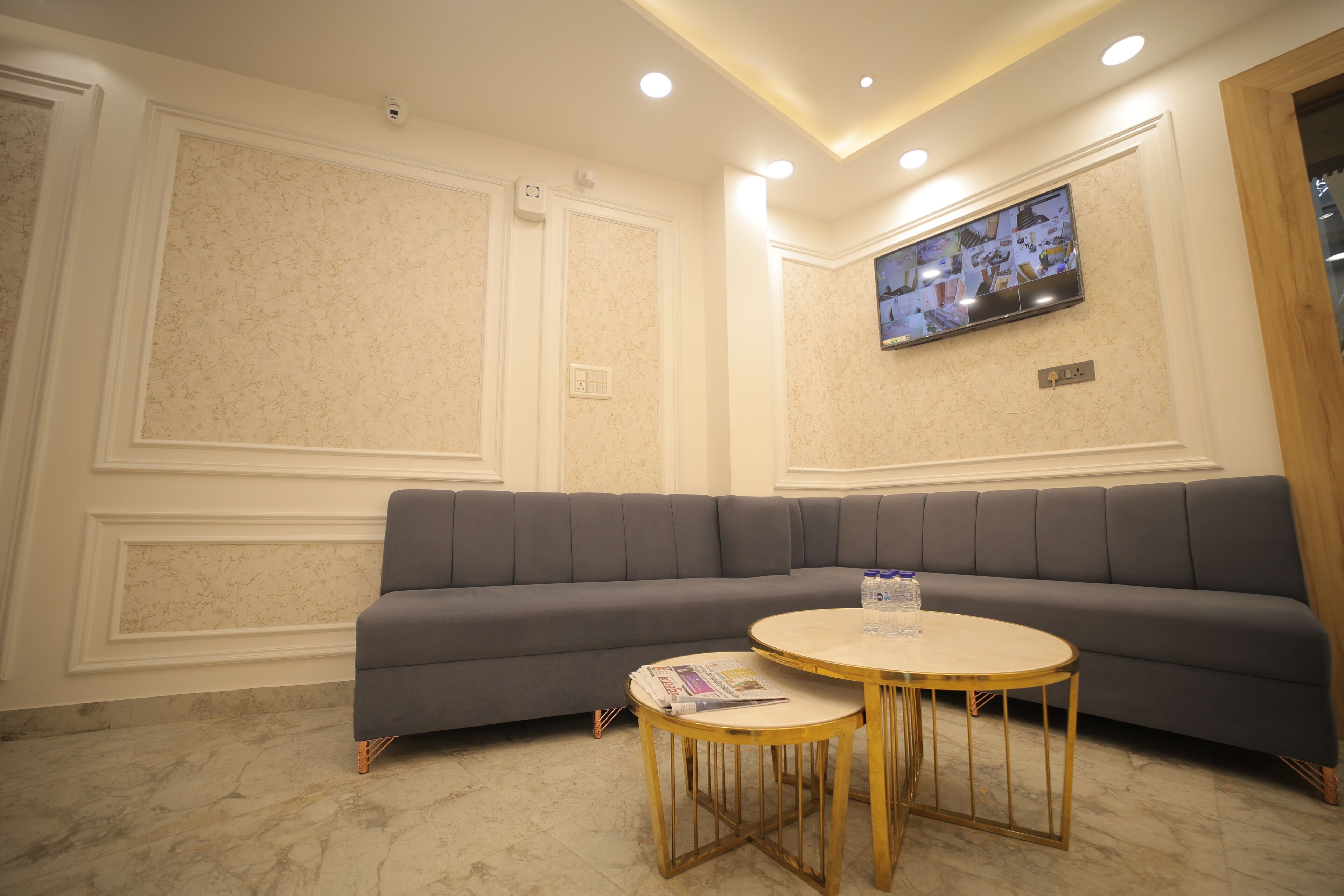 Una sala de estar moderna con un sofá seccional gris, una mesa de centro redonda de madera y un televisor de pantalla plana montado en la pared.