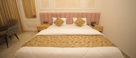 A neatly made bed with a patterned bedspread, a headboard with decorative panels, and a chair with a floral cushion.