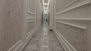 A long, narrow hallway with marble floors and walls, recessed lighting, and a symmetrical design. - BABA PALACE (Ayodhya)