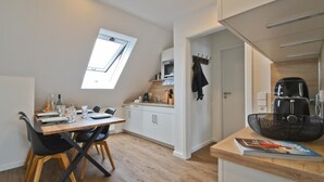 A compact kitchen with a dining area, a small oven, and a coffee machine. - Vacation apartment Wangerooge (Norderney)