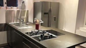 Une cuisine moderne dotée d’appareils électroménagers en acier inoxydable, d’un îlot central avec une plaque de cuisson et d’un four encastré.