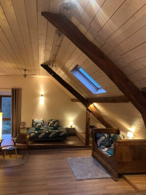 A cozy attic bedroom with a sloped ceiling, a skylight, a bed, a chair, and a small table. - Villa 240m², 6 chambres, avec jardin, vue Lac (Trévignin)