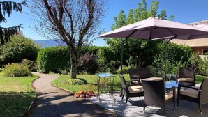 Une terrasse dotée de mobilier d’extérieur, d’une table et d’un parasol.