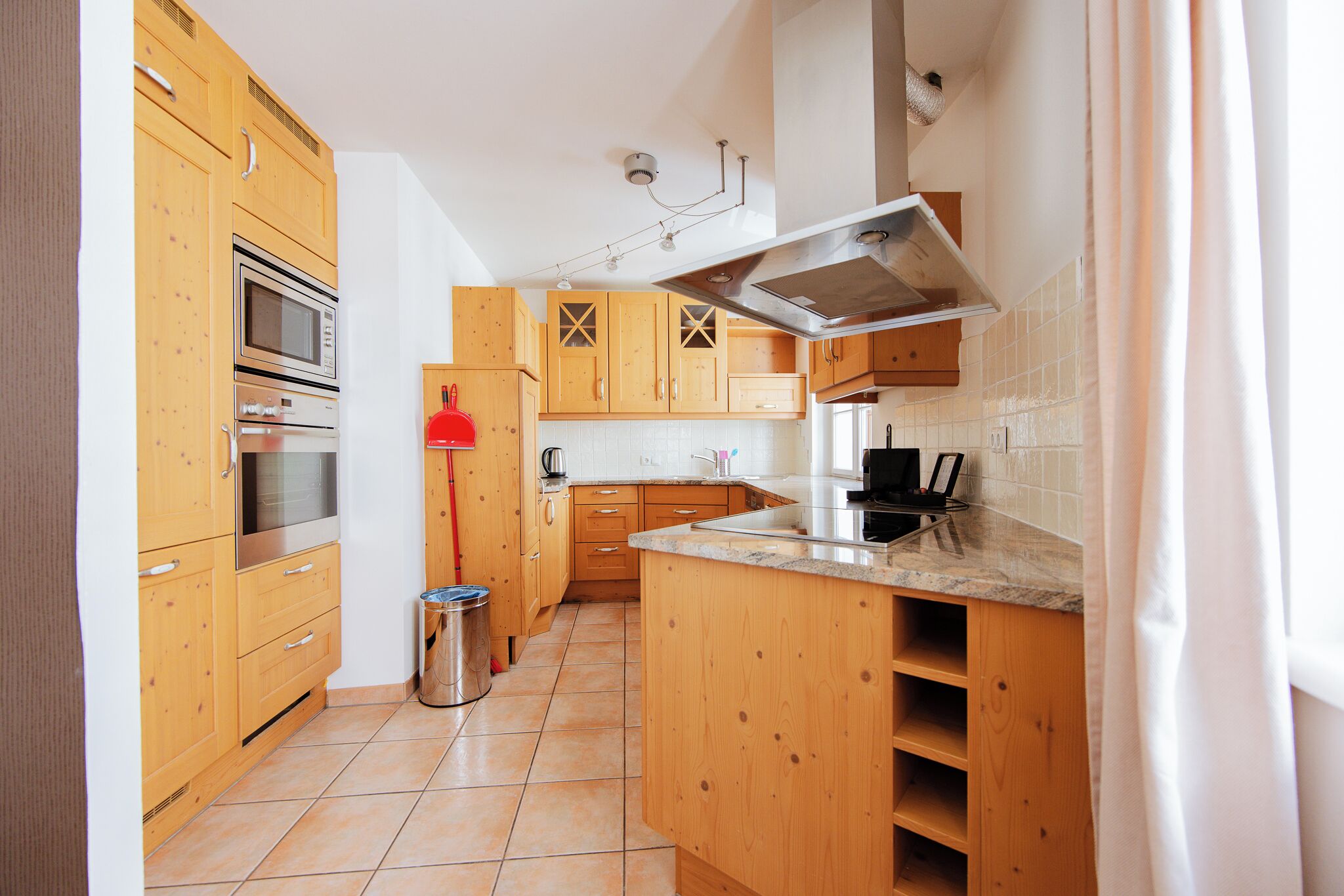 Une cuisine avec des meubles en bois, des appareils électroménagers en acier inoxydable et un dosseret carrelé.