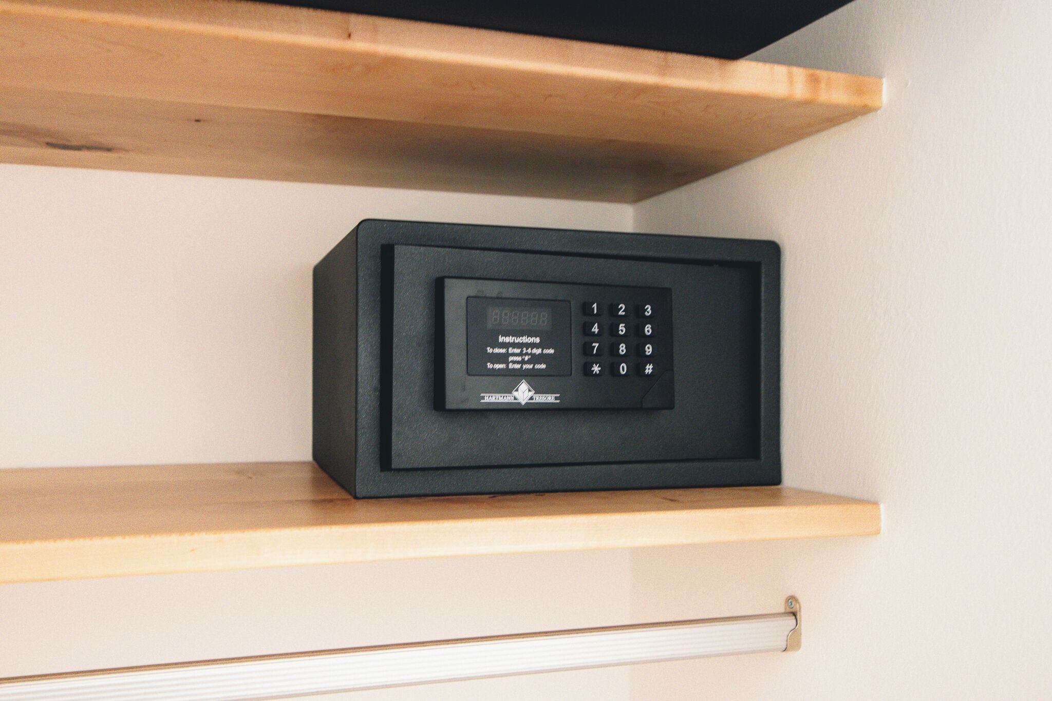 Un coffre-fort noir posé sur une étagère en bois.