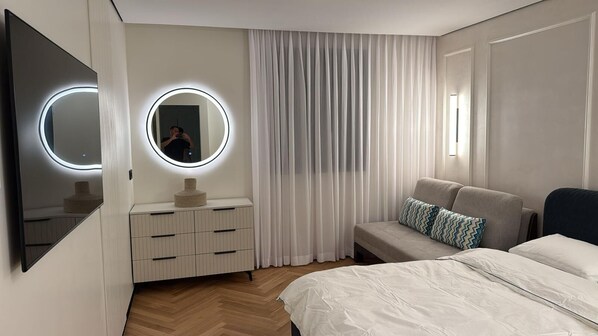 Een moderne slaapkamer met een bed, een kaptafel met spiegel en een bank.