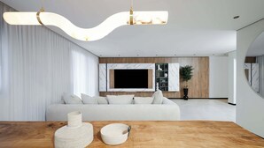 A modern living room with a large flat-screen TV, a wooden coffee table, and a white sofa. - Artemis  Luxury Apartment with Private Pool and Stunning Views in Tiberias (Tiberias)