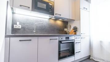 Una cocina moderna con horno integrado, microondas y encimera de acero inoxidable.