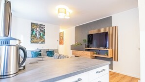 Una cocina moderna con hervidor, televisor de pantalla plana y un armario de madera.