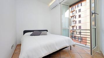 A bedroom with a bed, a window, and a view of a building.