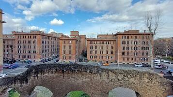 A multi-story building with a classical architectural style, featuring a central courtyard and a stone bridge in the foreground.