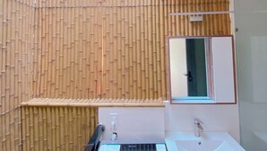 A modern bathroom with a bamboo wall, a black sauna, a white sink, and a mirror. - Lunaria Maison - Central Park (Ho Chi Minh City)