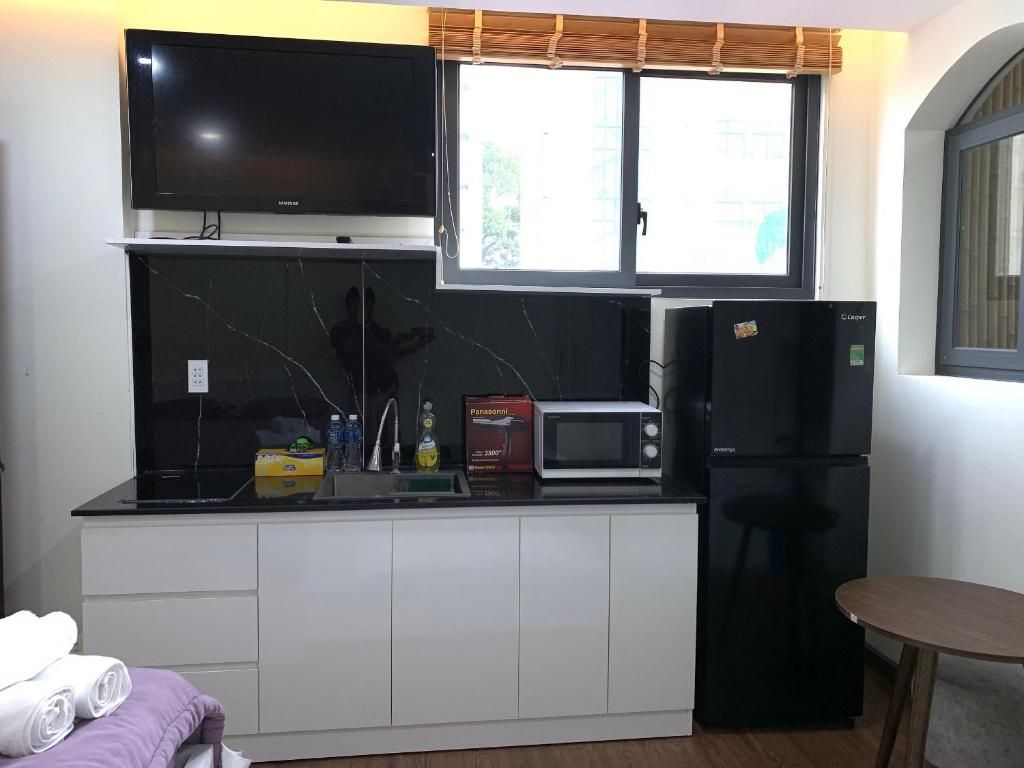 Cocina compacta con televisor de pantalla plana, microondas y refrigerador.