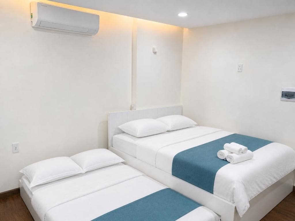 Habitación de hotel con dos camas, aire acondicionado de pared y un pequeño dispositivo montado en la pared.