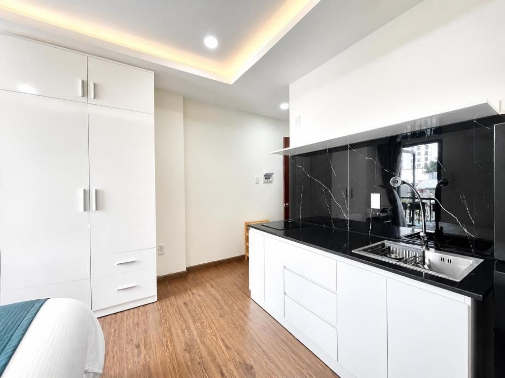 Una cocina moderna con armarios blancos, encimera negra y estufa integrada.