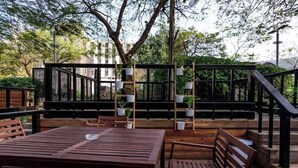 An outdoor seating area with wooden tables and benches, surrounded by potted plants and a metal fence. - Luxury Suite in Tiberias (Tiberias)