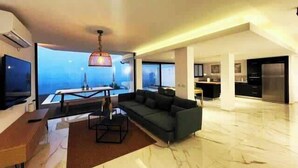 A modern living room with a large sofa, a dining table, and a view of the sea through large windows. - Villa Selavi  Private Infinity Pool (Tiberias)